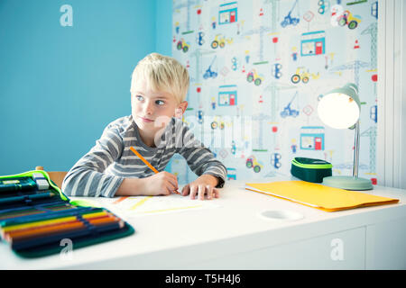 Boy doing homework at desk in children's room Stock Photo
