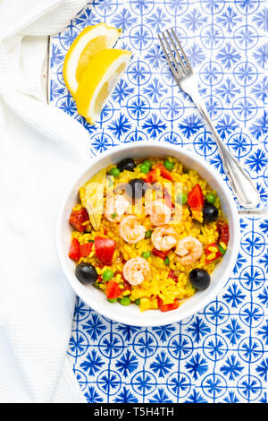 Paella with rice, bell pepper, tomato, artichoke, pea, black olive, curcuma and shrimps Stock Photo