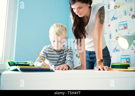 Mother helping son doing homework at desk Stock Photo