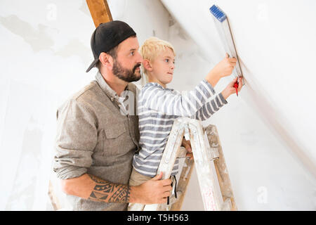 Father and son working on loft conversion using water level Stock Photo