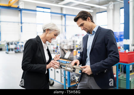 Businessman and senior businesswoman examining workpiece in a factory Stock Photo