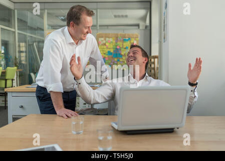Two businessmen with laptop talking in office Stock Photo