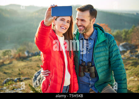 Happy couple on a hiking trip in the mountains taking a selfie Stock Photo