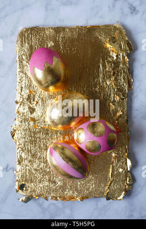 Four painted Easter eggs on golden background and marble Stock Photo