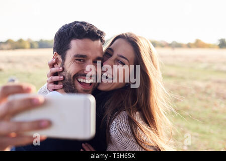 Happy couple taking a selfie in a park Stock Photo