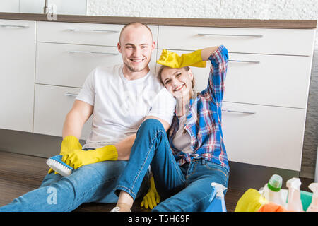 Young couple husband and wife do the house cleaning. The guy and the girl wash the kitchen with a mop and cloth, teamwork, fun Stock Photo