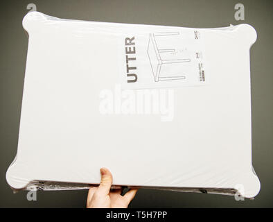 Paris, France - Apr 16, 2019: Man hand holding against gray background IKEA plastic UTTER table  Stock Photo
