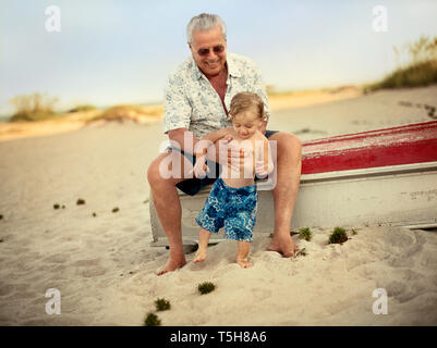 Grandfather holding grandson on beach Stock Photo