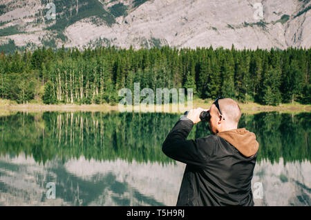 Young man looking through binoculars in National Park Stock Photo