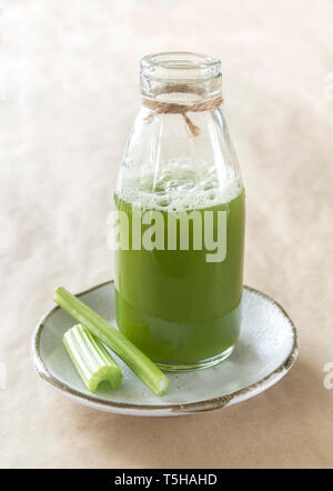 A small bottle of celery juice on a plate with two celery sticks Stock Photo