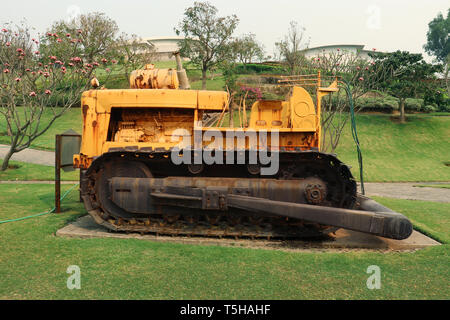 Old yellow rusty crawler tractor in the field. Old crawler tractor on green garden High resolution image gallery. Stock Photo