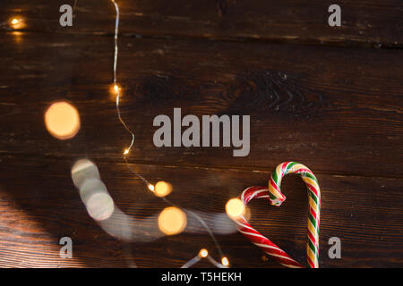 Christmas candies and lights on wooden background. Christmas concept, mint striped lollipops and a garland of lights, as a background for the x-mass Stock Photo