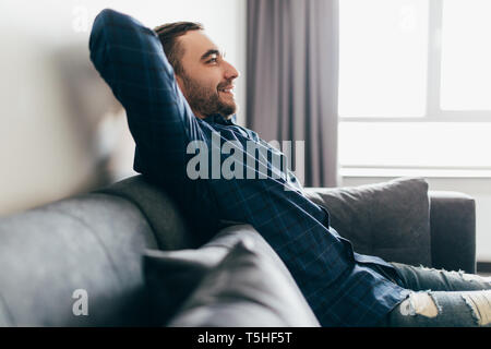 Handsome young man holding hands behind head while sleeping on the couch Stock Photo