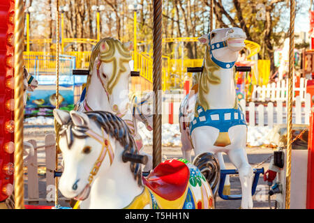 Children outdoor colourful vintage Merry-Go-Round flying horse carousel in amusement holliday park in city. Attraction detail horses and animals with  Stock Photo
