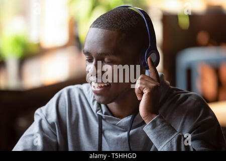 Serene african american guy wearing headphones listening favorite music Stock Photo