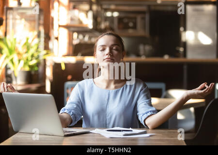 Young woman sitting at table in cafe relaxing do meditation Stock Photo