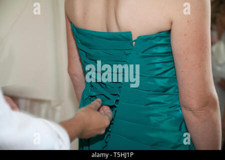 Bridesmaid dress being done up from behind in close up, teal green dress being laced up before the wedding ceremony Stock Photo