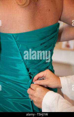 Bridesmaid dress being done up from behind in close up, teal green dress being laced up before the wedding ceremony Stock Photo