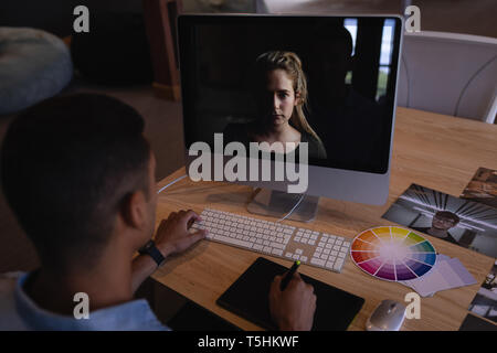 Male graphic designer using graphic tablet at desk in office Stock Photo