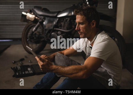 Bike mechanic using digital tablet in garage Stock Photo