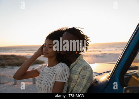 Romantic couple leaning at car on beach Stock Photo