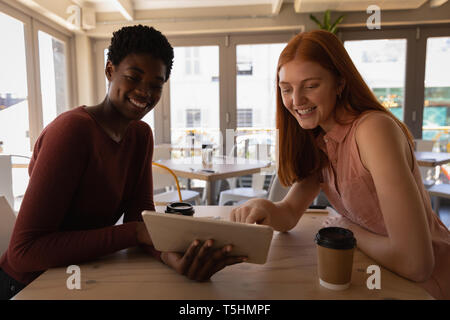 Female friends using digital tablet in a cafe Stock Photo