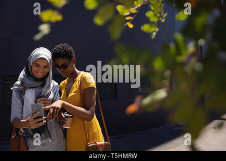 Female friends taking selfie with mobile phone in the city street Stock Photo