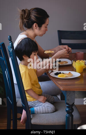 Mother and son enjoying breakfast on dining table in kitchen Stock Photo