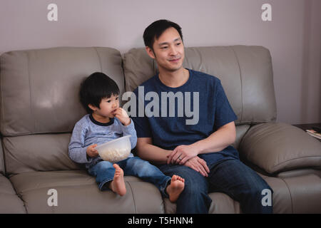 Father and son sitting on sofa at home Stock Photo