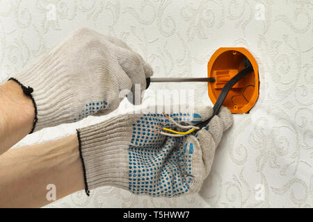 hands of an electrician install the socket box on the wall Stock Photo