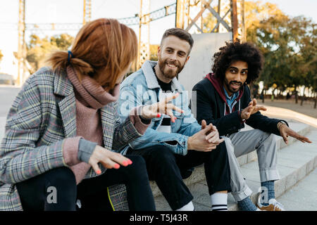 Three happy friends sitting outdoors alking Stock Photo