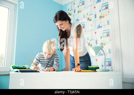 Mother helping son doing homework at desk Stock Photo