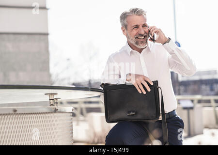 Happy mature businessman talking on cell phone outdoors Stock Photo