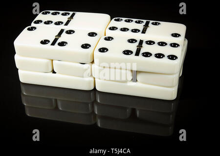 Stacks of Dominoes on a black reflective surface Stock Photo