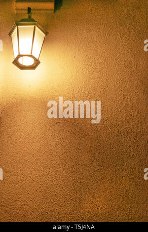 Small lantern mounted on an exterior yellow concrete wall Stock Photo