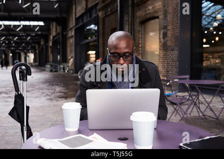 Portrait of businessman working on laptop at coworking space Stock Photo