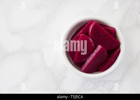 Picked beets in a white bowl on a marble surface Stock Photo