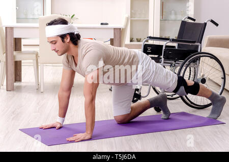 Injured young man doing exercises at home Stock Photo