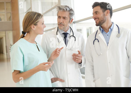 Doctors and nurse talking in hospital corridor Stock Photo