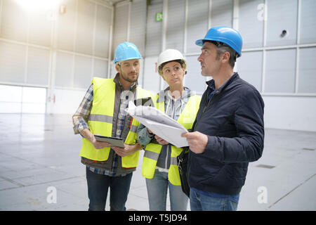 Team of construction workers talking in empty warehouse Stock Photo