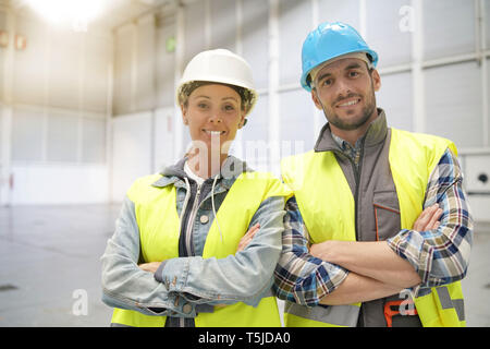 Male and female concstruction coworkers in warehouse looking at camera Stock Photo