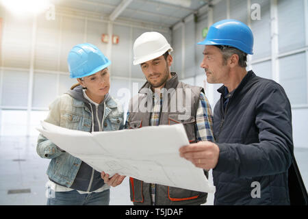 Team of construction workers talking in empty warehouse Stock Photo