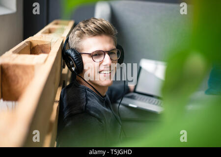 Smiling young man listening to music with headphones Stock Photo