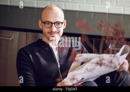 Man sitting in kitchen, reading newspaper Stock Photo