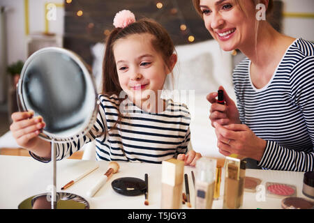 Mother and daughter applying make up together, using lipstick Stock Photo