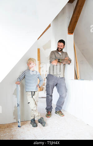 Portrait of smiling father and son working on loft conversion Stock Photo