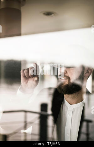 Businessman standing at the window, using VR glasses Stock Photo