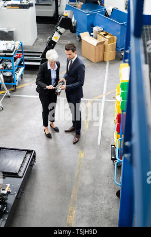 Businessman and senior businesswoman examining workpiece in a factory Stock Photo