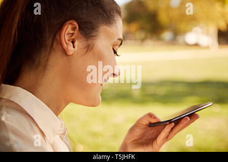 Happy young woman using smartphone in a park Stock Photo