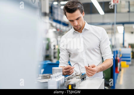 Businessman examining workpiece in a factory Stock Photo